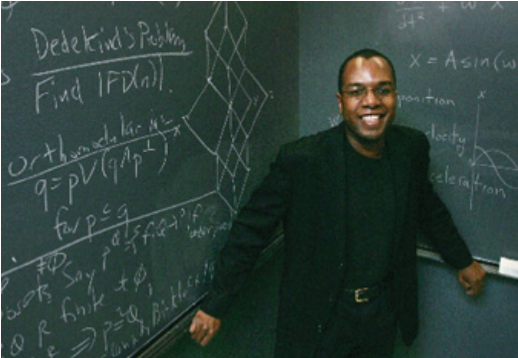 A picture of Dr. Jonathan Farley in front of a chalkboard with math symbols.